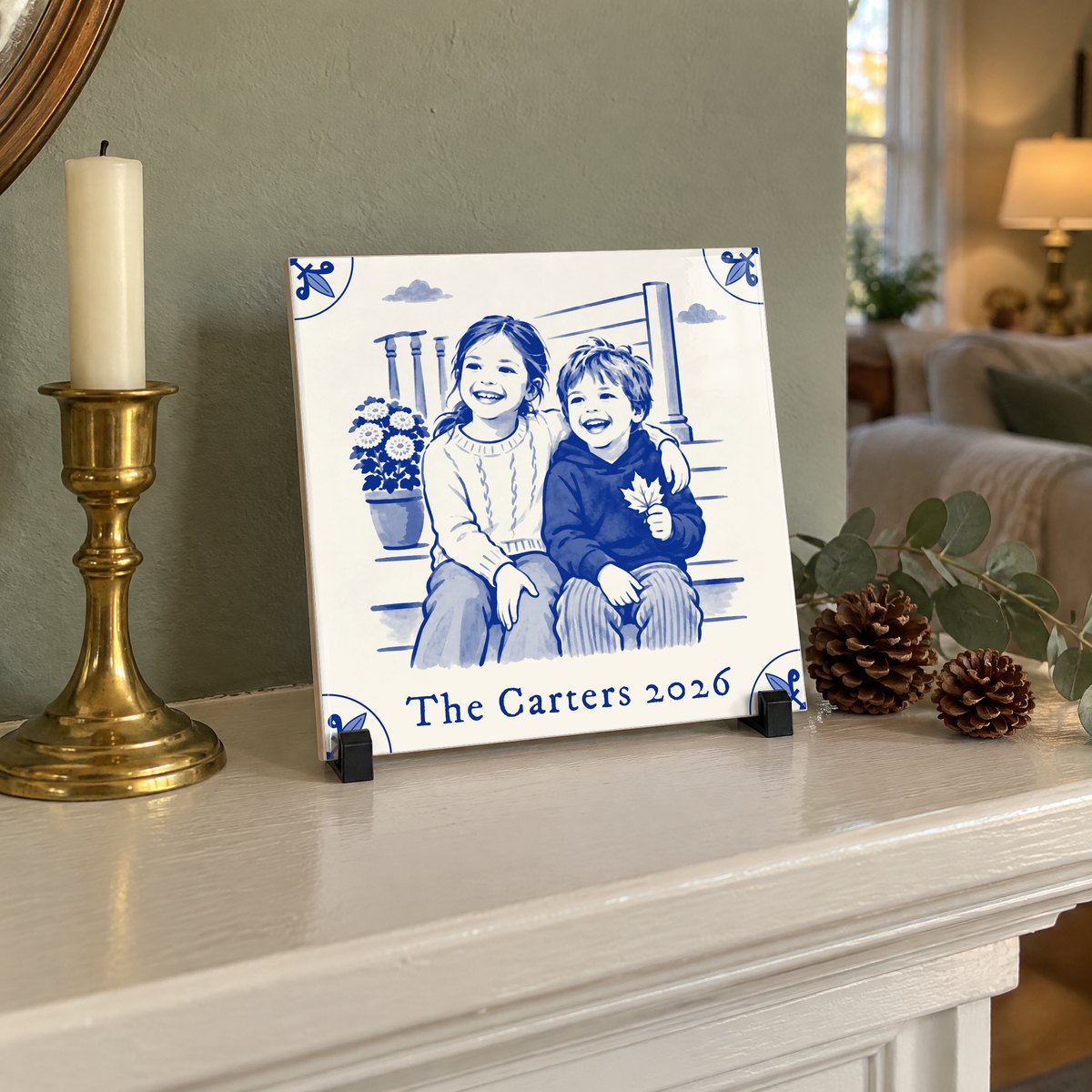 A square Delft-blue ceramic tile of two children on porch steps, standing on a white fireplace mantel