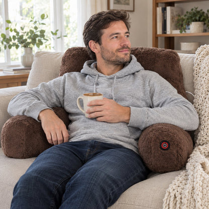 Man relaxing on a sofa against the heated backrest pillow, holding a mug