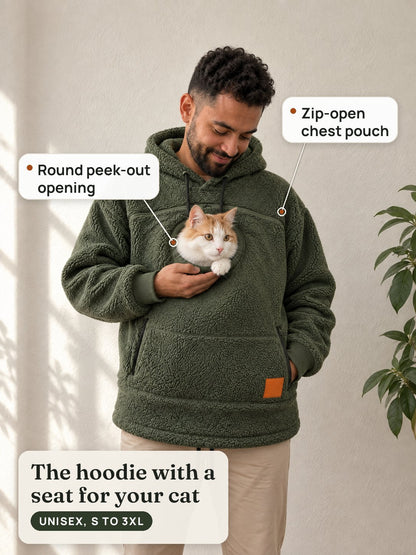 A man in the olive cat pouch hoodie smiles down at an orange-and-white cat peeking out of the round chest opening