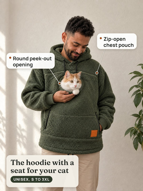 A man in the olive cat pouch hoodie smiles down at an orange-and-white cat peeking out of the round chest opening