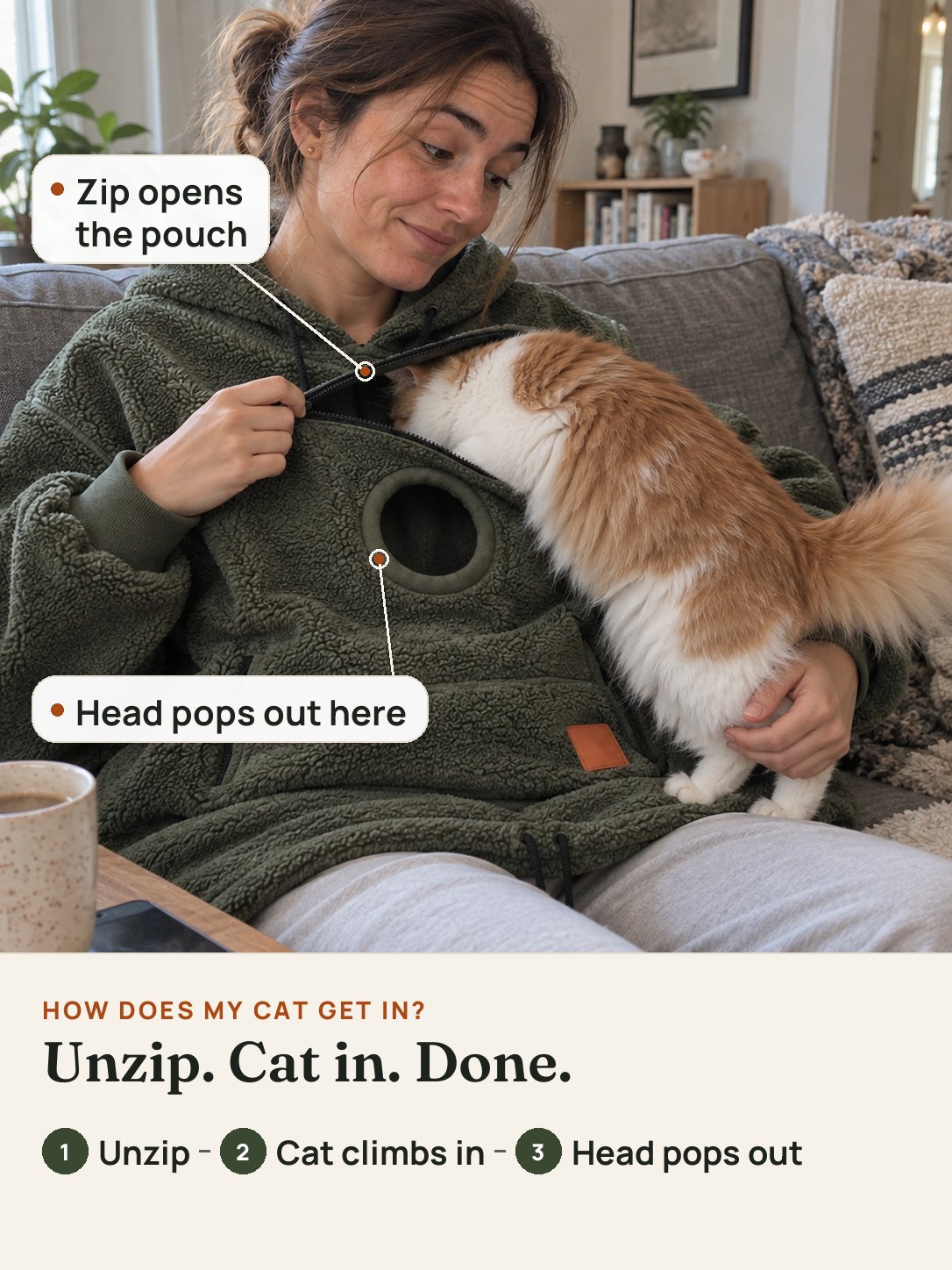 The chest zip of the hoodie held open while the orange-and-white cat climbs into the pouch; its head pops out of the round opening below