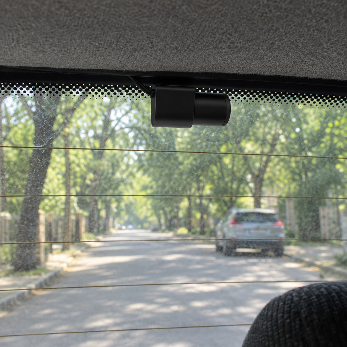 Close-up of the small rear camera stuck at the top of the rear window, cable tucked into the roof lining