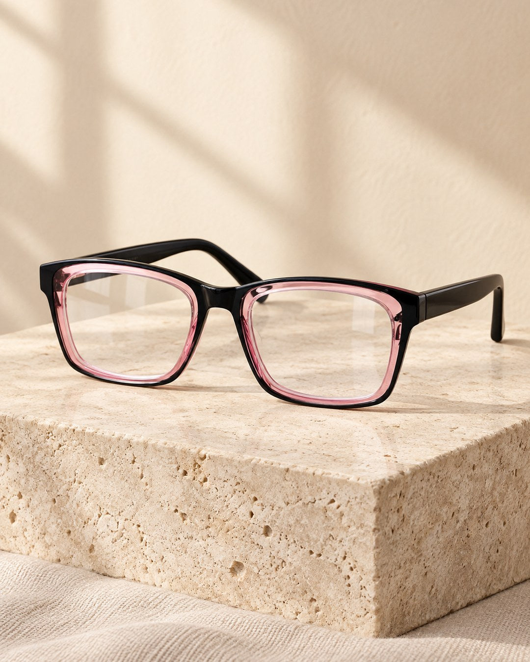 Progressive photochromic reading glasses, Black & Rose frame, on a travertine stone