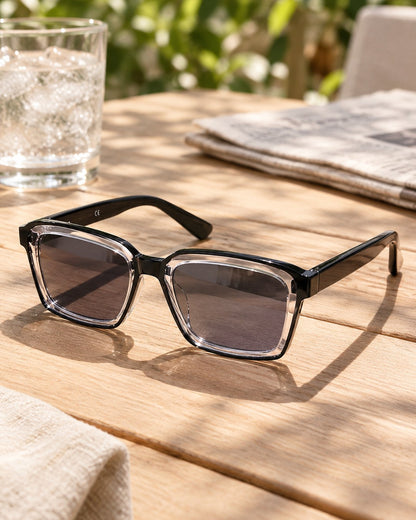 The reading glasses with lenses darkened like sunglasses on a sunny cafe table
