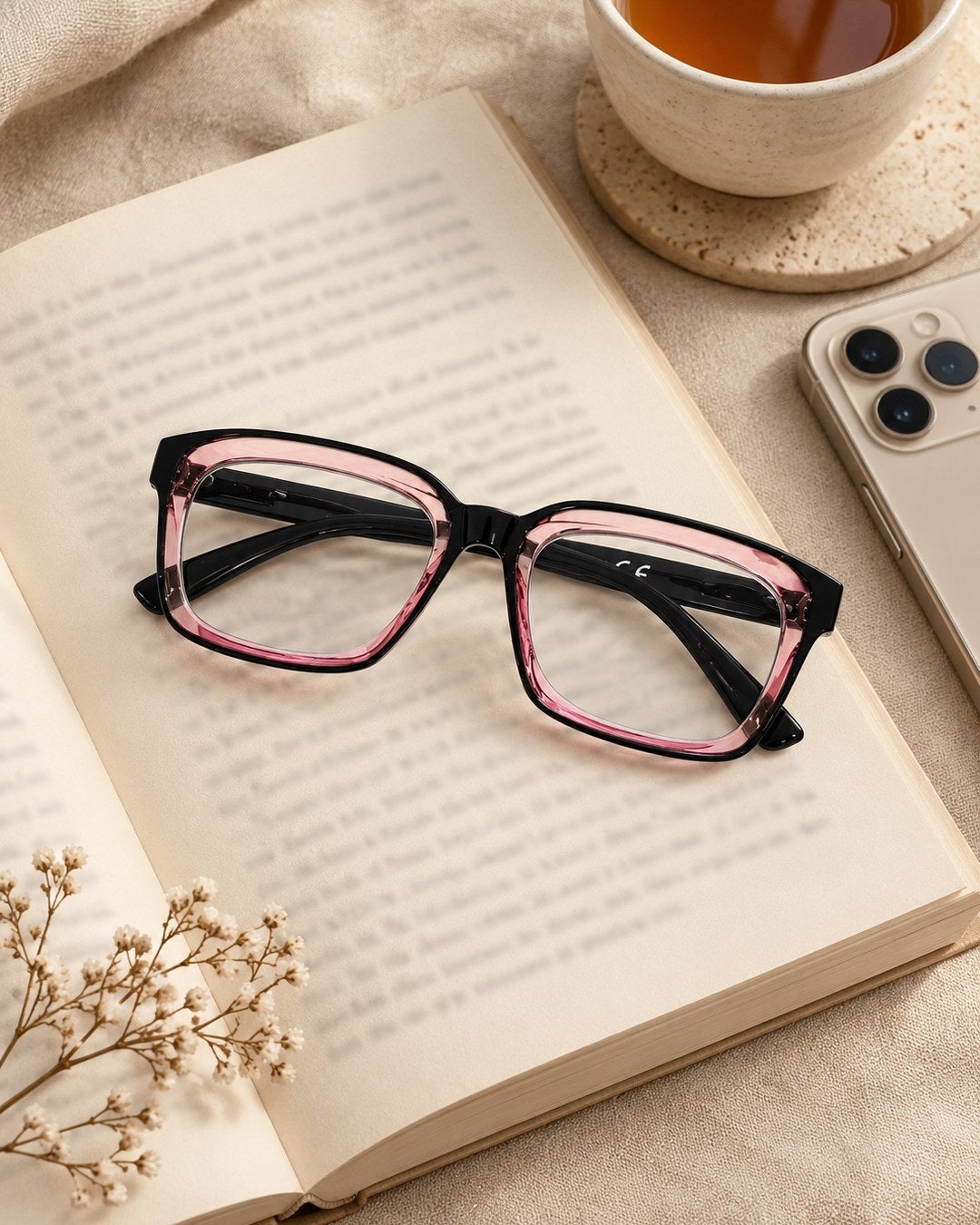 The Black & Rose reading glasses resting on an open book next to a cup of tea