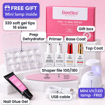 Complete soft gel nail tips kit in a studio, each item labeled: 320 soft gel tips in 16 sizes, gift box, prep dehydrator, primer, base coat, top coat, nail glue gel, shaper file 100/180, free mini UV/LED lamp, USB cable