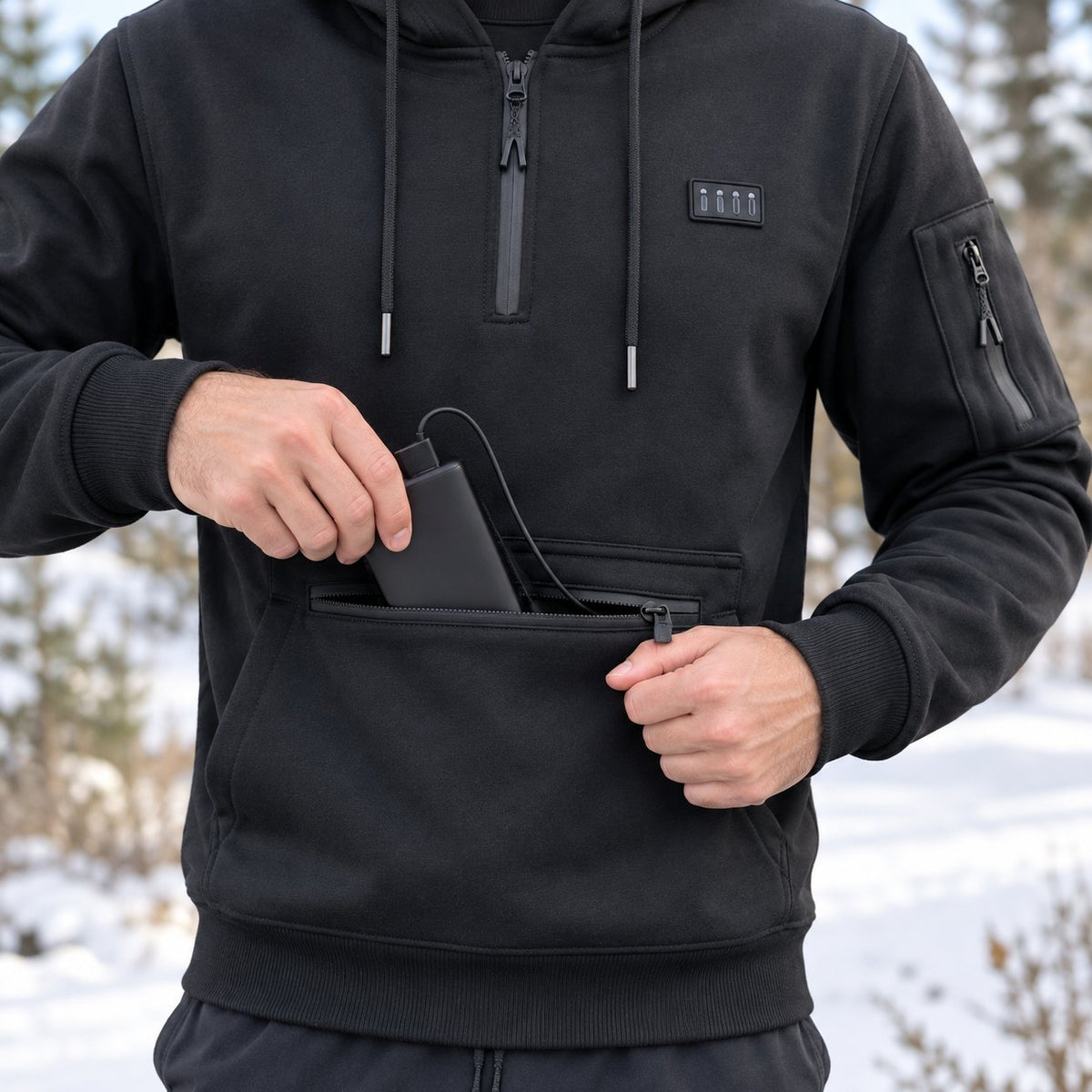 Hand sliding the USB power bank, cable plugged in, into the zip front pocket of the heated hoodie