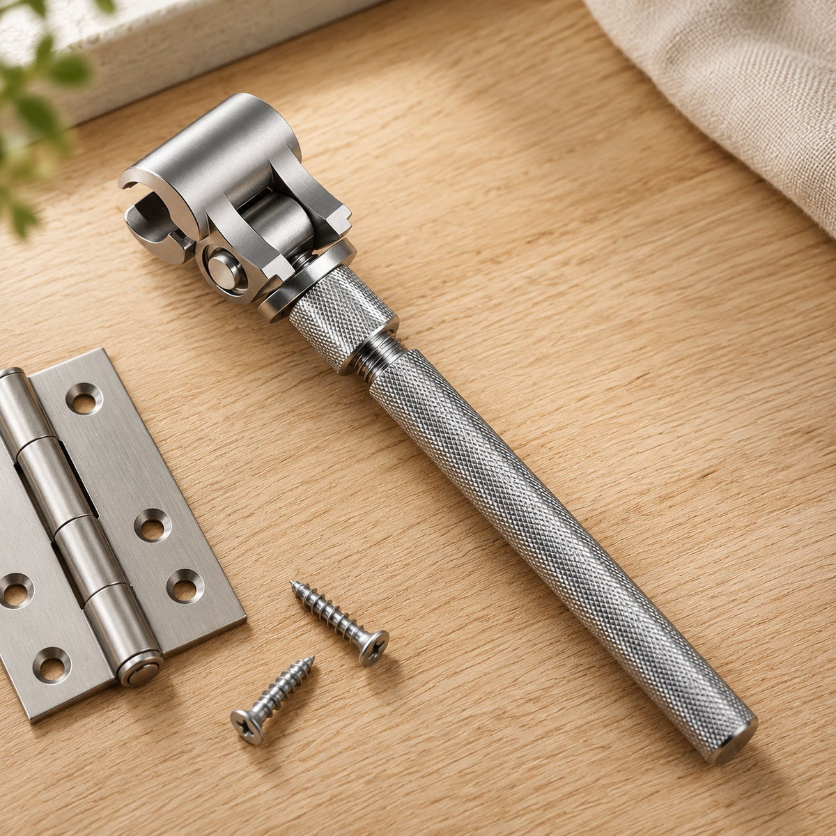 Adjustable stainless door hinge wrench on a workbench next to a door hinge