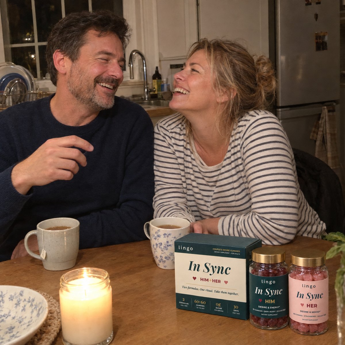 A couple laughing at their kitchen table at night with tea, a candle and the In Sync box