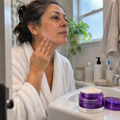 Woman smoothing the cream along her jawline in her bathroom