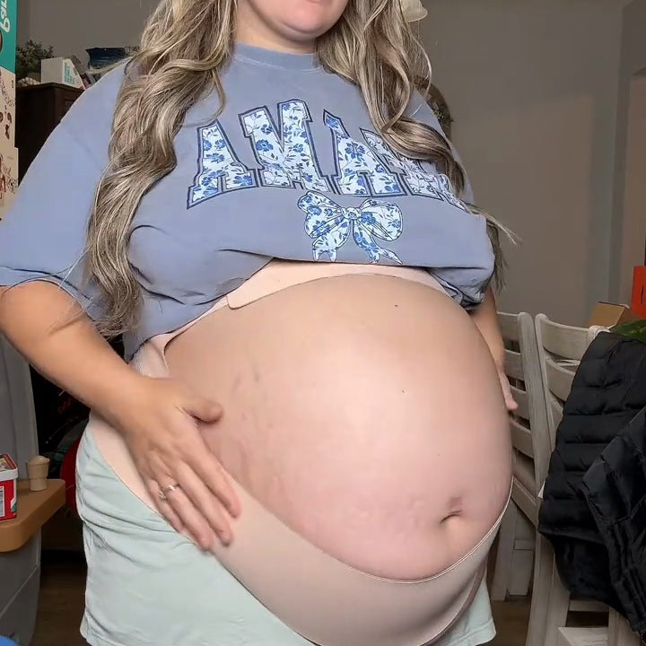 Pregnant woman with a big bump wearing the nude support band that lifts her belly from below