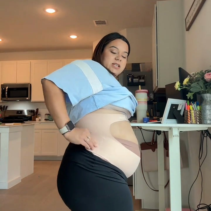 Side view of a pregnant woman wearing the nude band under her bump at home