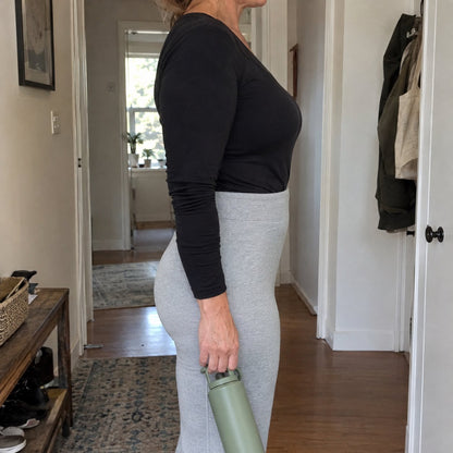 Side view of a woman in thin grey leggings: smooth lower belly, no underwear lines