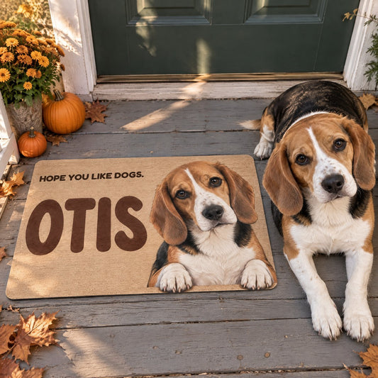 Doormat printed with a beagle named Otis and the words Hope you like dogs, in front of a green front door, with the real beagle lying beside it