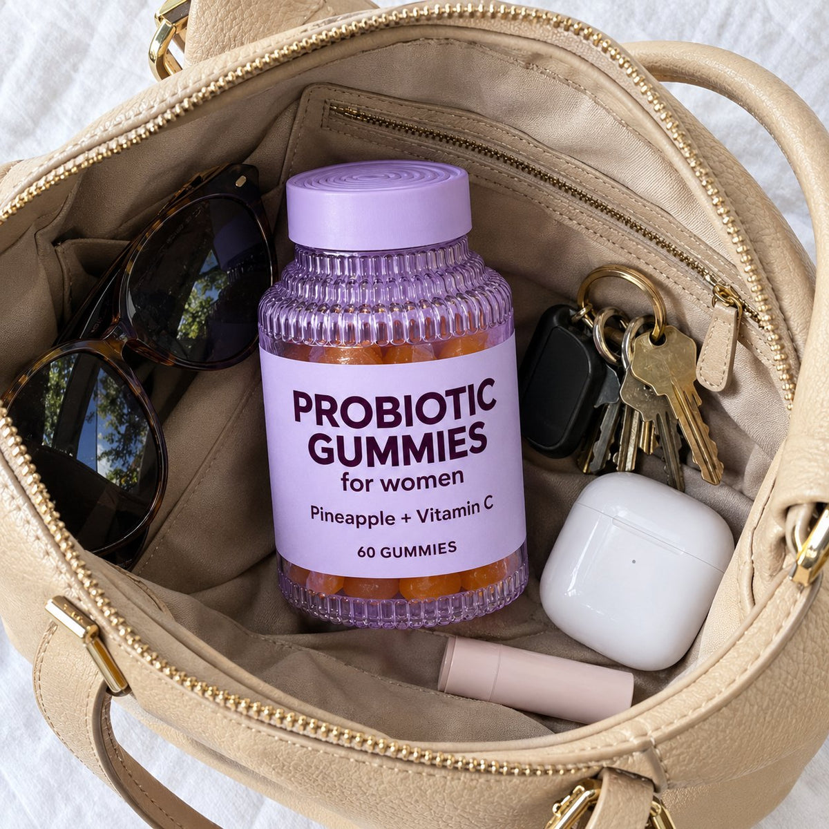 Probiotic gummies bottle in an open handbag with sunglasses and keys