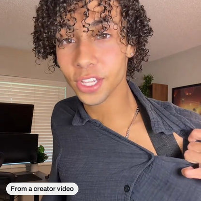 Frame from a creator video: he pulls his collar aside to show the strap under his shirt