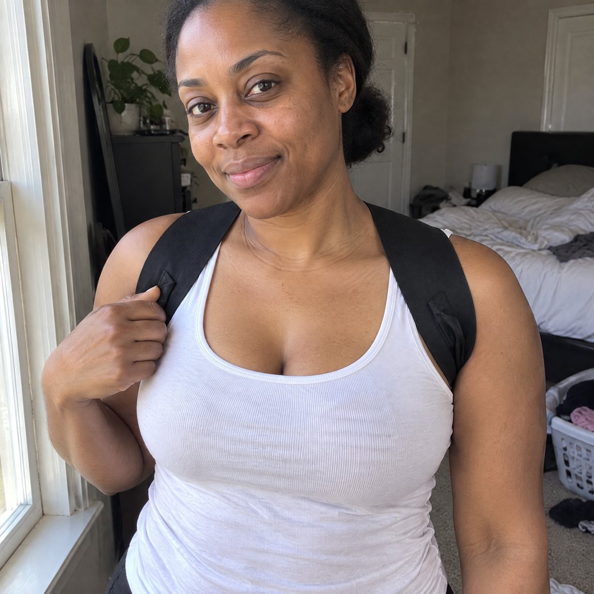 Woman wearing the black posture strap, bands over the front of both shoulders