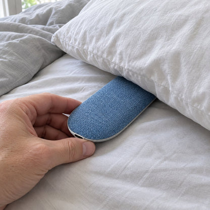 Hand sliding the speaker under a pillow