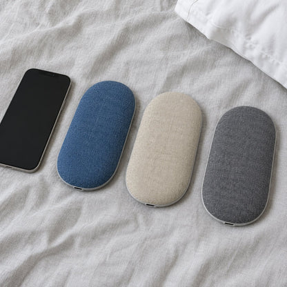 Three under-pillow speakers in blue, beige and gray next to a phone