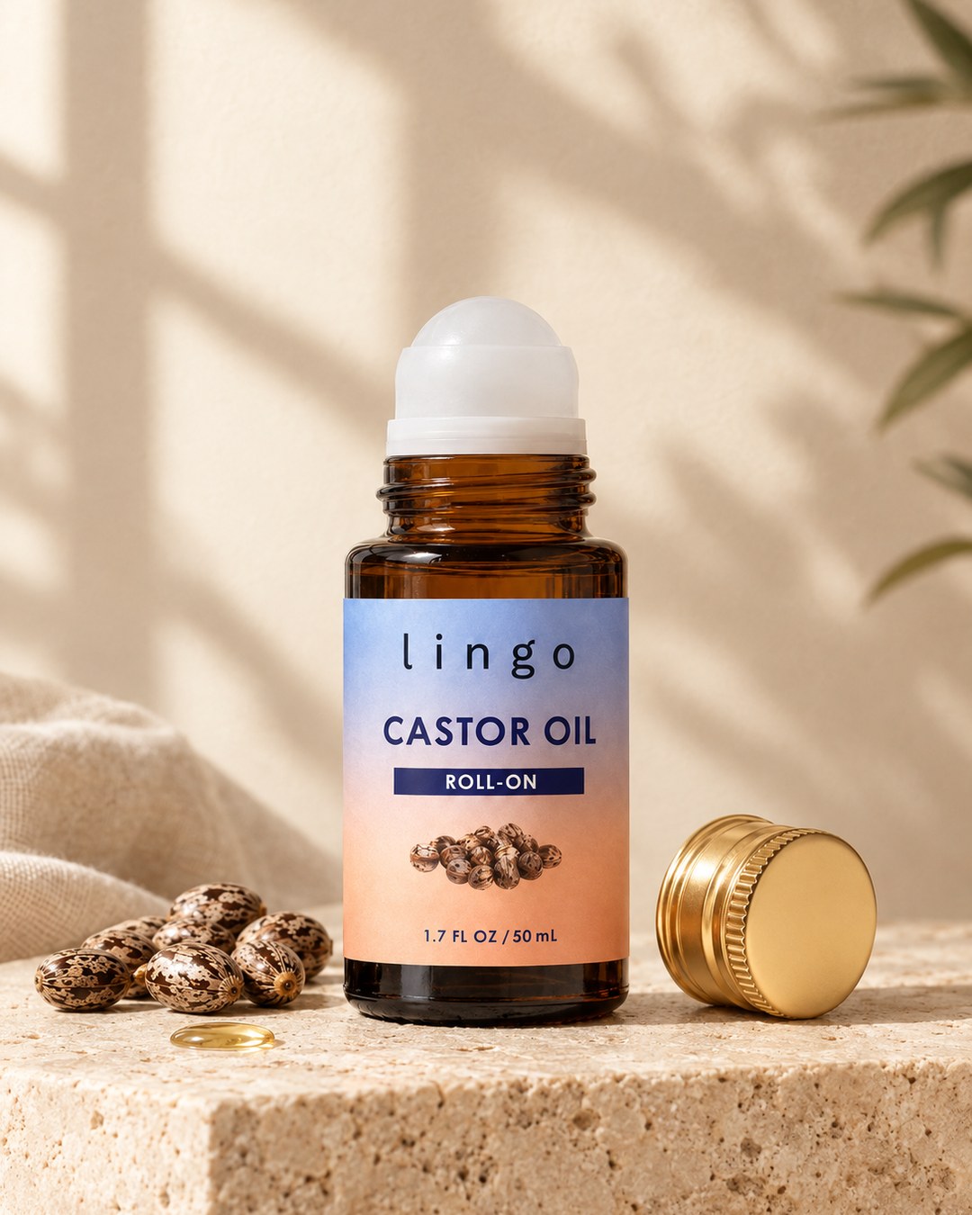 Castor oil roll-on, amber 50 mL bottle with a white roller ball and its gold cap on a travertine stone