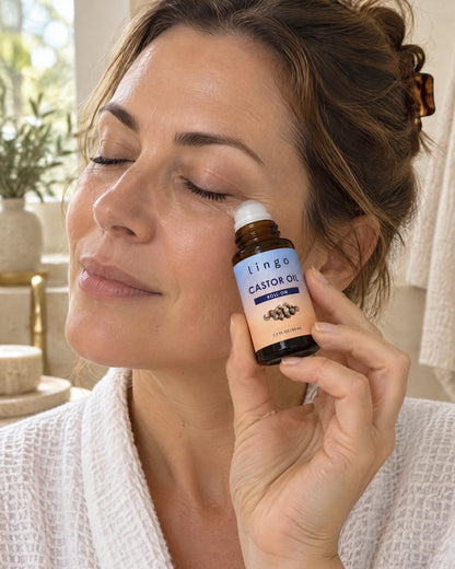 Woman with eyes closed rolling the castor oil roll-on under her eye