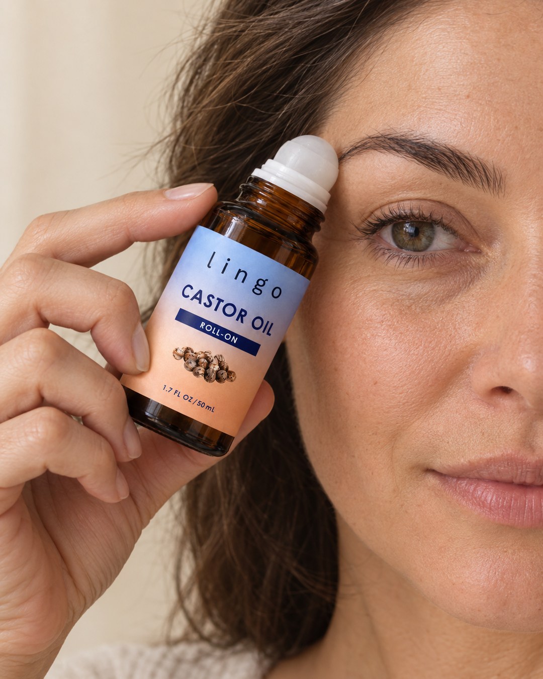 Woman rolling the castor oil roll-on along her eyebrow