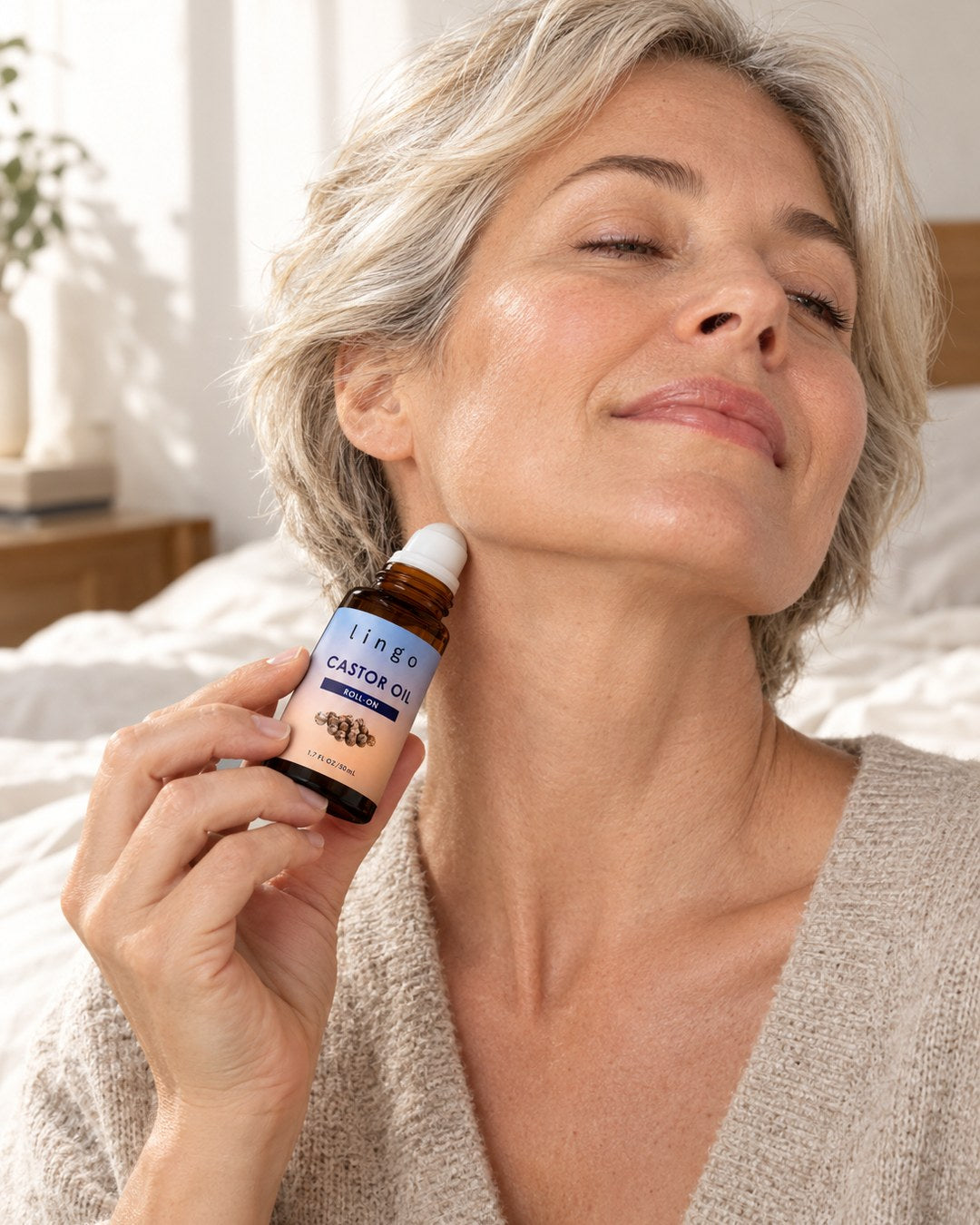 Woman rolling the castor oil roll-on along her jawline and neck in the morning