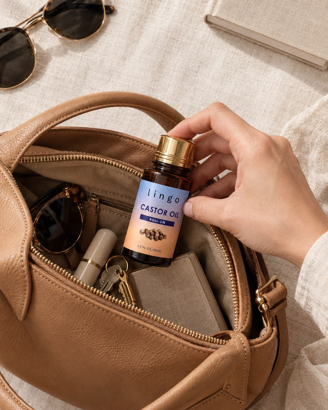 Hand putting the capped castor oil roll-on into an open leather handbag
