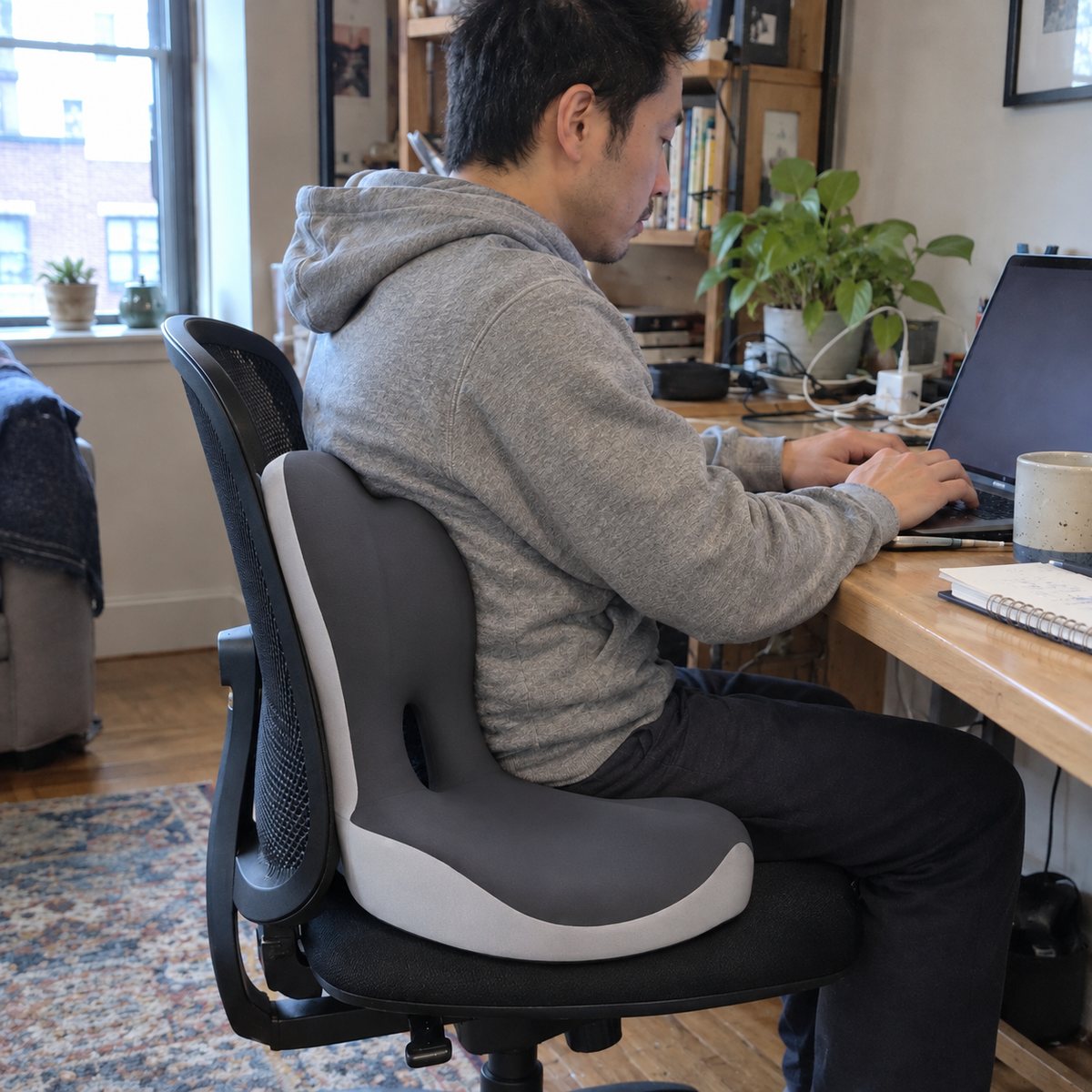 Man working at a home desk on an office chair fitted with the seat and lumbar cushion