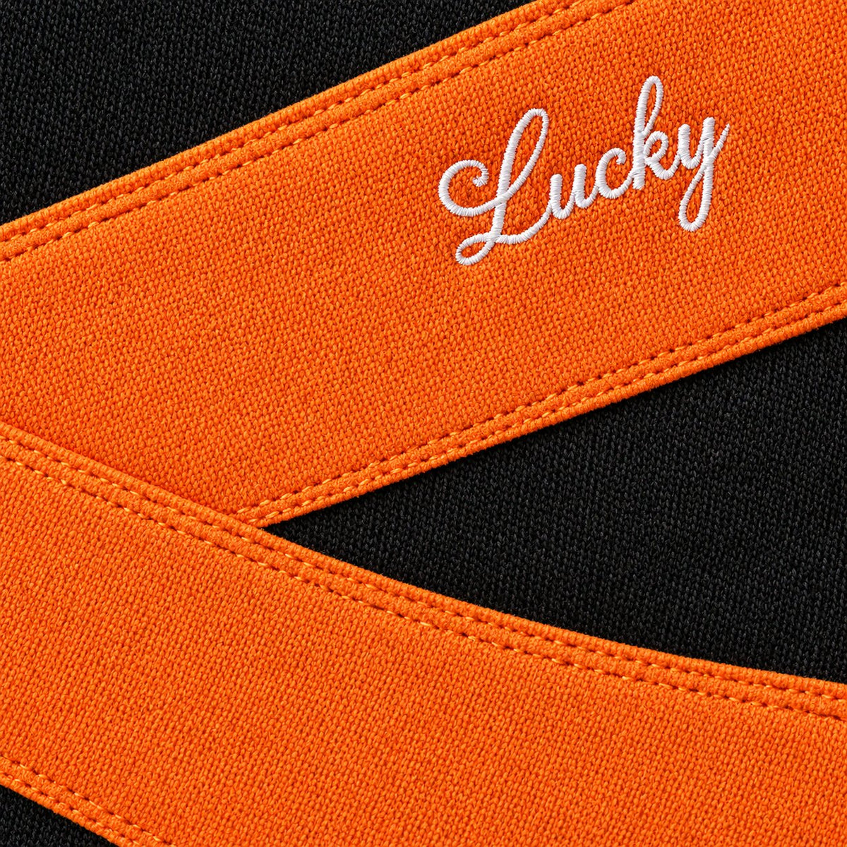 Close-up of the crossed orange band, its stitching and the small white script embroidery