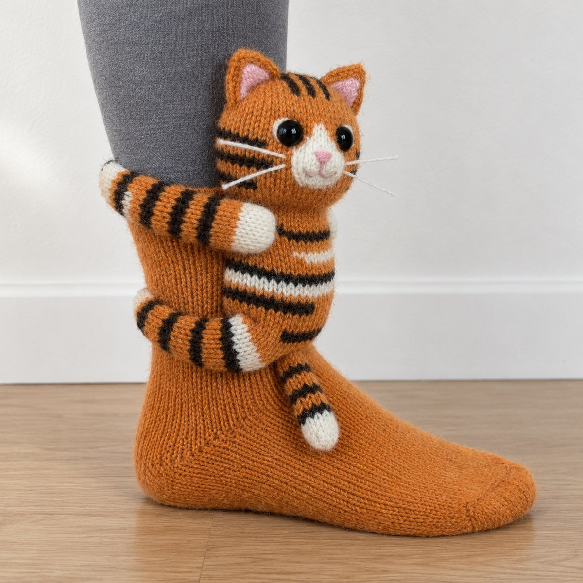 Orange knit sock with a 3D knitted orange tabby cat hugging the ankle
