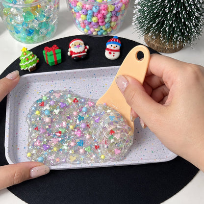 Hand rolling clear gel with beads and heart confetti on a tray with a scraper