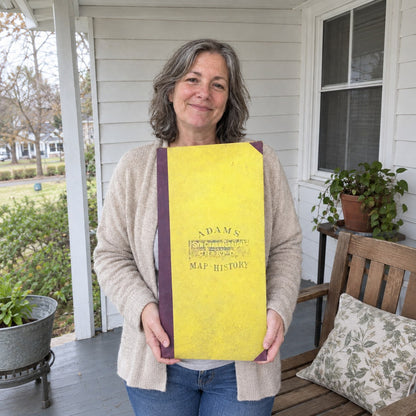 A woman holding the closed chart upright, showing how large the book is