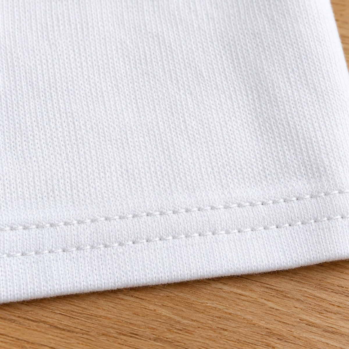 Close-up of the double-stitched hem of the white tank