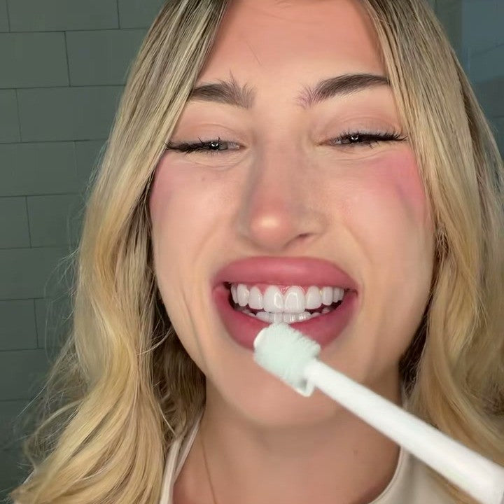 Woman smiling while brushing with the silicone roller toothbrush