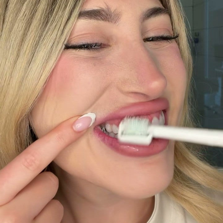 Woman lifting her lip while the silicone roller rolls along her teeth and gumline