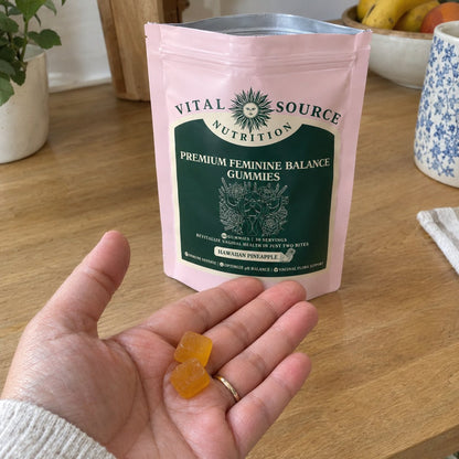 Two pineapple gummies in the palm, the bag behind