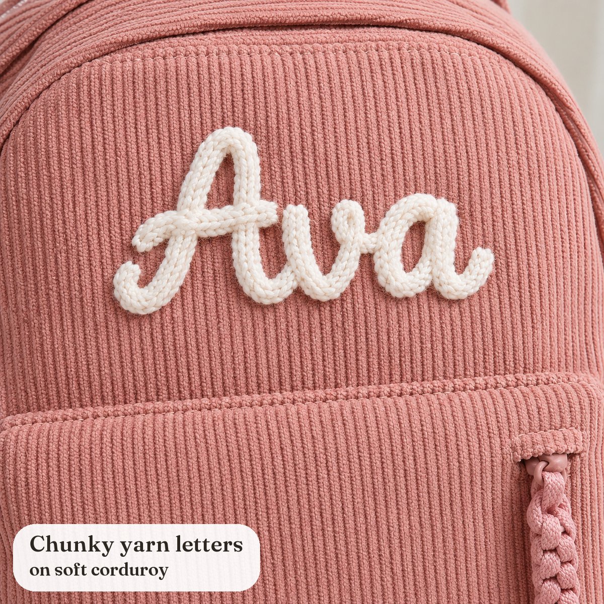 Close-up of the name Ava in chunky white yarn letters on pink corduroy